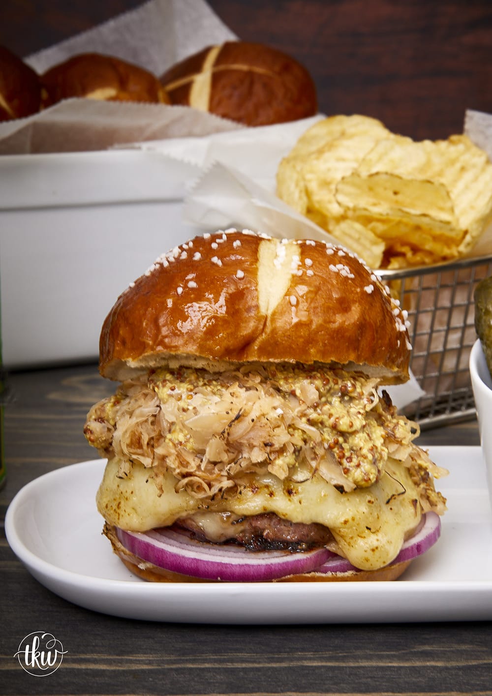 Prepare to take your taste buds on a flavor-packed journey of a perfectly grilled bratwurst burger stuffed with sauerkraut and gooey Swiss cheese. A slice of red onion, crispy sauerkraut, and whole-grain mustard on a pretzel bun will make this your new favorite burger! The Best Grilled German Bratwurst Burgers Stuffed With Cheese & Sauerkraut, grilled German bratwurst, juicy Lucy German burgers, Oktoberfest burgers, stuffed burgers, pork burgers, sausage burgers, grilled burgers